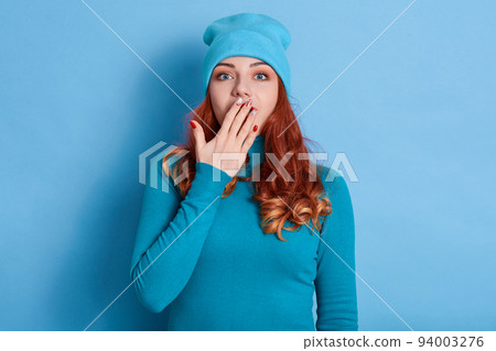 Surprised shocked astonished amazed girl covering mouth with hand with beautiful manicure, hears unbelievable news, young beautiful woman on blue background. 94003276