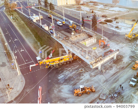view from a height of a large construction site. construction of a bridge in the city center. construction of a new overpass on a fenced section of the road view from a height of a large construction site. construction of a bridge in the city center. construction of a new overpass on a fenced section of the road 94003799
