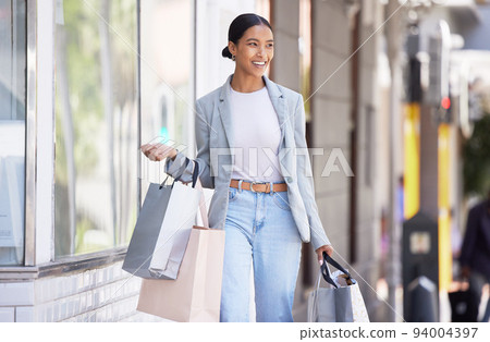 Happy, smile and fashion woman shopping for new clothes in style and buying modern outfits with her money. Fun, lifestyle and young shopper walking outside of a retail store smiling with happiness Happy, smile and fashion woman shopping for new clothes in style and buying modern outfits with her money. Fun, lifestyle and young shopper walking outside of a retail store smiling with happiness 94004397