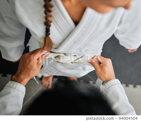 Woman wearing karate belt at fitness training class from coach, learning dojo exercise at gym and doing workout at sports studio from above. Top view of female student getting ready for self defense 94004504