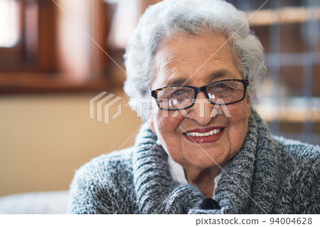 Portrait beautiful elderly woman smiling sitting on sofa at home enjoying retirement 94004628