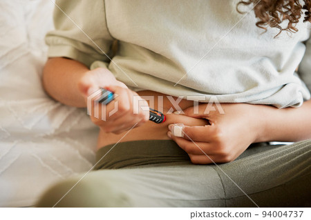 Diabetes, diabetic woman with a chronic disease injecting herself with insulin treatment at home. Closeup of a female taking glucose medication or medicine to control blood sugar levels Diabetes, diabetic woman with a chronic disease injecting herself with insulin treatment at home. Closeup of a female taking glucose medication or medicine to control blood sugar levels 94004737