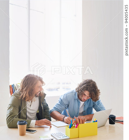 College students working together two young men brainstorming ideas for project sitting at desk using laptop computer in class 94005435