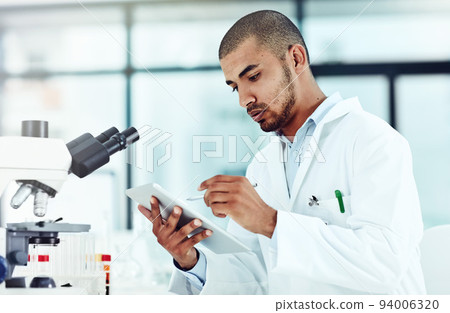 Serious male scientist working on a tablet reviewing an online phd publication in a lab. Laboratory worker updating health data for a science journal. Medical professional document clinical trial Serious male scientist working on a tablet reviewing an online phd publication in a lab. Laboratory worker updating health data for a science journal. Medical professional document clinical trial 94006320