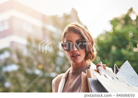 Stylish fashion model shopping in the city enjoying her weekend vacation. A rich, trendy and carefree young female with an expensive lifestyle and elegant style walking outdoors on a buying spree Stylish fashion model shopping in the city enjoying her weekend vacation. A rich, trendy and carefree young female with an expensive lifestyle and elegant style walking outdoors on a buying spree 94006650