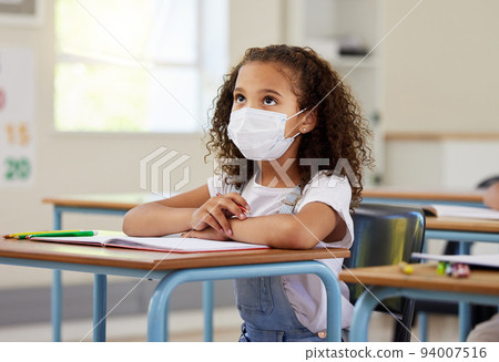Child or student in class during covid, wearing a mask for hygiene and protection from corona virus flu. Little kindergarten, preschool or elementary school girl sitting in a classroom ready to learn 94007516