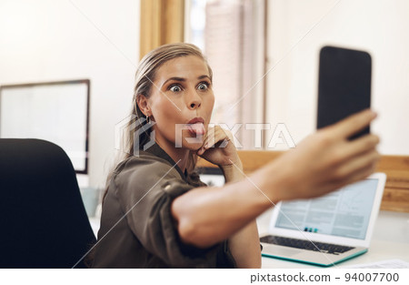 Phone selfie with a playful business woman having fun, being goofy and joking while working in her office. Young female sticking out her tongue and making a face at work while feeling carefree Phone selfie with a playful business woman having fun, being goofy and joking while working in her office. Young female sticking out her tongue and making a face at work while feeling carefree 94007700