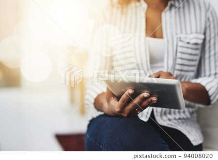Tablet technology in the hands of a woman browsing social media, surfing the internet or chatting online with flare and copyspace. Closeup of a female sending an email message or reading news 94008020