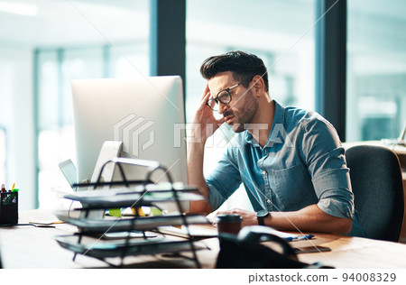 Stress, anxiety and worry with a business man feeling frustrated, irritated and annoyed with work and deadlines. Unhappy and negative male employee suffering from a headache or migraine in his office 94008329