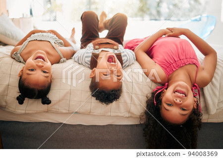 Silly kids playing upside down on bed enjoy and having fun together in parents bedroom. Happy children or siblings bonding and enjoying childhood together at cozy, warm and comfortable family home 94008369