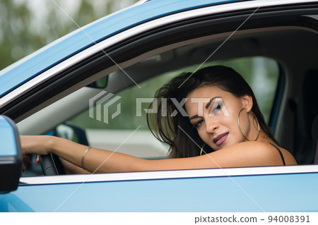 Black-haired woman driver shows confident posing in car 94008391