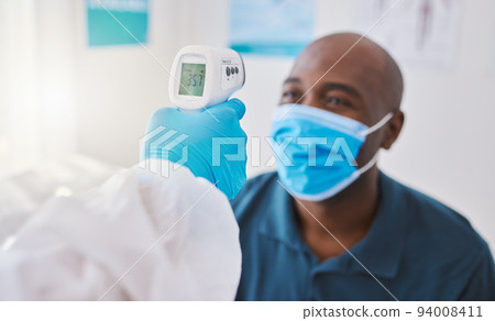 Checking for covid, corona or fever with a patient wearing a mask for hygiene, sickness or flu symptoms in a health clinic. Medical doctor holding a thermometer to scan the temperature of a patient Checking for covid, corona or fever with a patient wearing a mask for hygiene, sickness or flu symptoms in a health clinic. Medical doctor holding a thermometer to scan the temperature of a patient 94008411