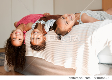Fun, playful and silly kids lying on a bed with cute hairstyle and smiling portrait. Little siblings relaxing, playing indoors showing growth, child development and childhood innocence 94008628