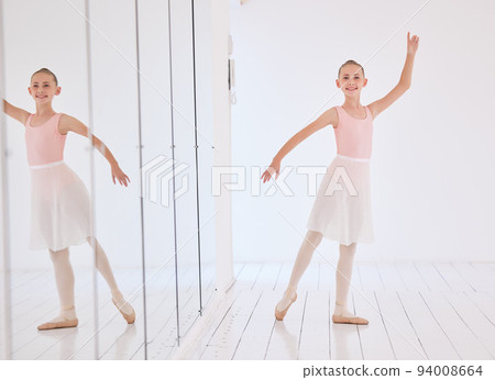Happy ballet dancer girl stretching in a dance studio with mirror reflection and portrait. Smile face of a learning child dancing in a class in pink princess costume for a performance Happy ballet dancer girl stretching in a dance studio with mirror reflection and portrait. Smile face of a learning child dancing in a class in pink princess costume for a performance 94008664