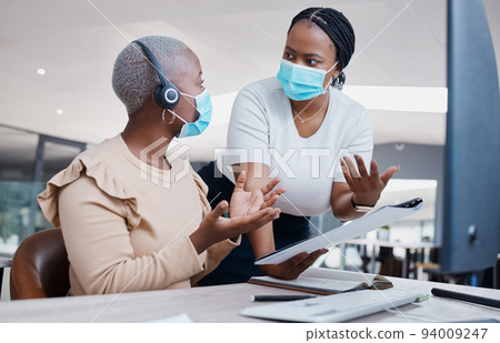 Manager consulting a call center agent about business paperwork with face masks in covid pandemic. Black, young and customer support worker discussing a work mistake with her mentor in an office. Manager consulting a call center agent about business paperwork with face masks in covid pandemic. Black, young and customer support worker discussing a work mistake with her mentor in an office. 94009247