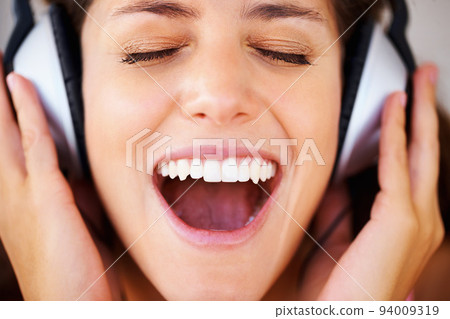 Music, radio and podcast with a woman in headphones listening to and streaming audio while feeling excited, carefree and positive. Happy, freedom and shouting with the face of a young female closeup 94009319