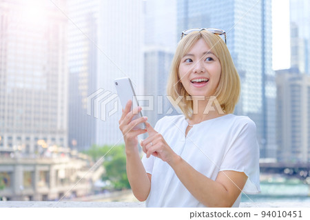 A blonde woman using a smartphone abroad 94010451