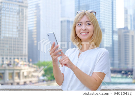 A blonde woman using a smartphone abroad 94010452