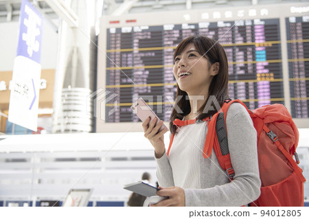 A backpacker woman operating a smartphone in the airport 94012805