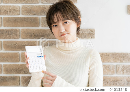 有計算器和嚴厲的表情的一個少婦 94013248