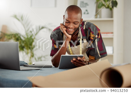 Checking an online order of fashionable style on his company website or internet app. Fashion, design and clothing industry with a trendy tailor thinking working on a tablet in his studio or workshop Checking an online order of fashionable style on his company website or internet app. Fashion, design and clothing industry with a trendy tailor thinking working on a tablet in his studio or workshop 94013250