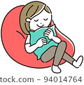 Young woman sitting on a beaded cushion and relaxing holding it 94014764