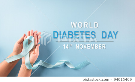 World diabetes day awareness concept. Hand holding blue ribbon, symbolic bow color raising awareness in diabetes day on pastel background,  14 November. 94015409