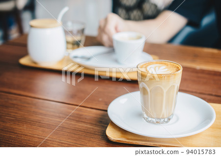 A glass cup of Piccolo latte on wooden table in the coffee shop. A glass cup of Piccolo latte on wooden table in the coffee shop. 94015783