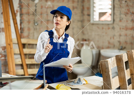 Female foreman making task list during works in building under construction Female foreman making task list during works in building under construction 94016378