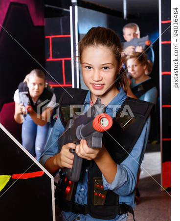 Portrait of teenager girl with laser gun having fun with her family on lasertag arena 94016484