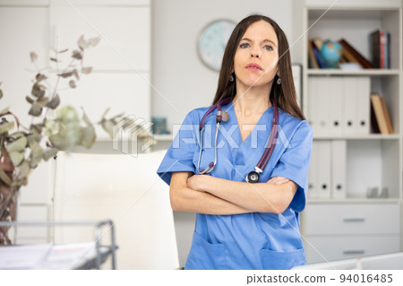 Woman doctor standing inside office, looking at camera 94016485