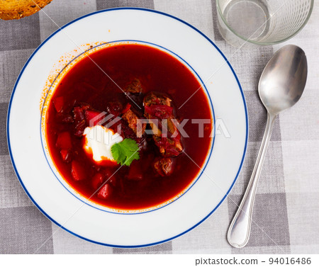 Homemade beetroot soup with vegetables and meat decorated by sour cream and parsley 94016486
