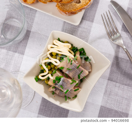 Pieces of herring served with green peas and onions. Appetizer fish on table Pieces of herring served with green peas and onions. Appetizer fish on table 94016698