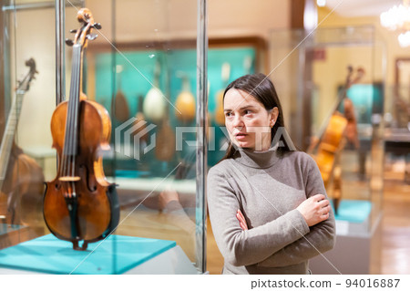 Interested brunette visiting exhibition of medieval musical instruments in museum 94016887
