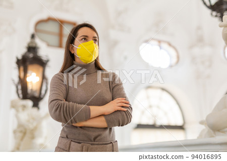 Woman tourist in mask admiring interiors of medieval palace 94016895