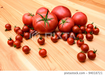 Multiple tomatoes and many mini tomatoes arranged on a wooden table Multiple tomatoes and many mini tomatoes arranged on a wooden table 94018721