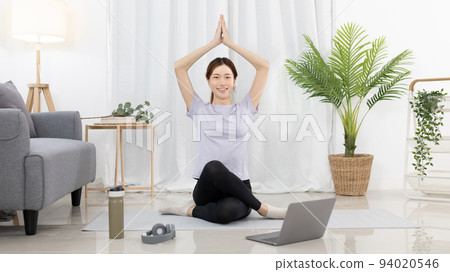 Beautiful Asian woman in sportswear is warming up or doing light exercises in the house with dumbbells and a protein shake or bottle of water and using a laptop at home, Healthy exercise. Beautiful Asian woman in sportswear is warming up or doing light exercises in the house with dumbbells and a protein shake or bottle of water and using a laptop at home, Healthy exercise. 94020546
