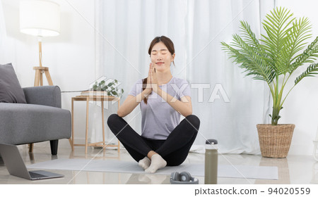 Beautiful Asian woman in sportswear is warming up or doing light exercises in the house with dumbbells and a protein shake or bottle of water and using a laptop at home, Healthy exercise. Beautiful Asian woman in sportswear is warming up or doing light exercises in the house with dumbbells and a protein shake or bottle of water and using a laptop at home, Healthy exercise. 94020559