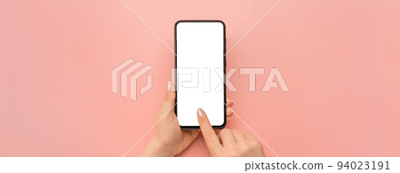 Hand holding cellphone device and touching screen on pink background. Isolated hands and smartphone on pink background. Female hand holding modern black cell phone in vertical position Hand holding cellphone device and touching screen on pink background. Isolated hands and smartphone on pink background. Female hand holding modern black cell phone in vertical position 94023191