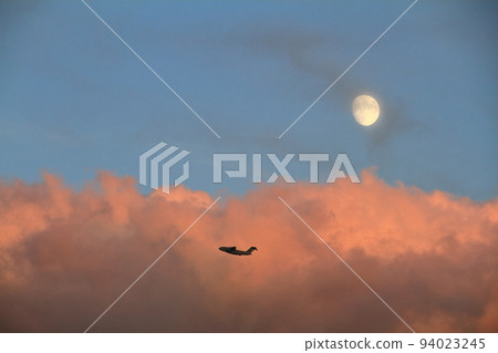 秋天的黃昏雲和月亮在夕陽和訓練飛行中的C-2運輸機中染色 94023245