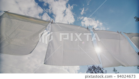 White bedding drying on a rope in the sun 94024673