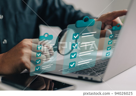 Businessman use magnifying glass with a checklist on clipboard paper. Successfully complete business assignments. 94026025
