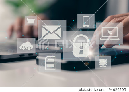 The concept of business, technology, the internet, and networking. A young businessman in the workplace, using a laptop, selects the security symbol on the virtual display. 94026505