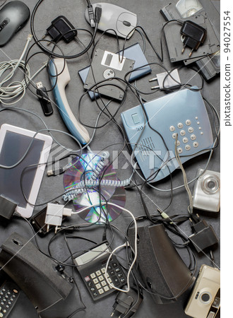 Old electronic devices on a dark background. The concept of recycling and disposal of electronic waste. Old electronic devices on a dark background. The concept of recycling and disposal of electronic waste. 94027554