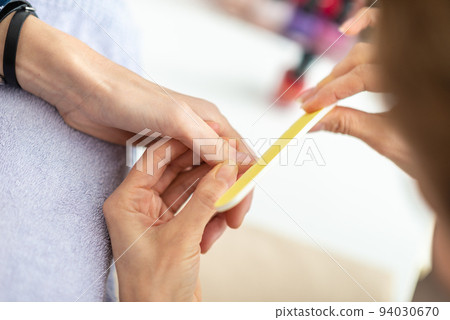 Closeup view of professional manicurist filing fingernail Closeup view of professional manicurist filing fingernail 94030670