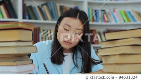 Student collecting information from different books, Beautiful asian girl in blue shirt gathering data for the paper. Self education concept. Student collecting information from different books, Beautiful asian girl in blue shirt gathering data for the paper. Self education concept. 94031324