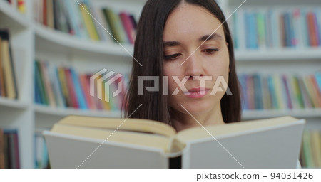 Beautiful young woman reading book in library of university. Self education concept. 94031426