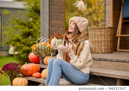 Cheerful young female enjoying her coffee break on the veranda 94031547