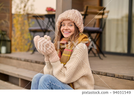 Woman seated on the veranda drinking a beverage Woman seated on the veranda drinking a beverage 94031549