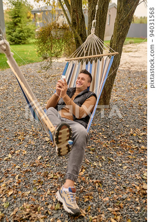 Joyful dark-haired male using his cellphone outdoors Joyful dark-haired male using his cellphone outdoors 94031568